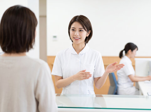 病院の受付で来院者を親切に案内するスタッフ