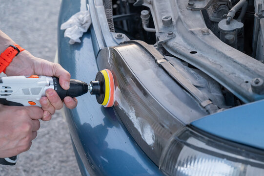The process of polishing car headlights outdoors. 
