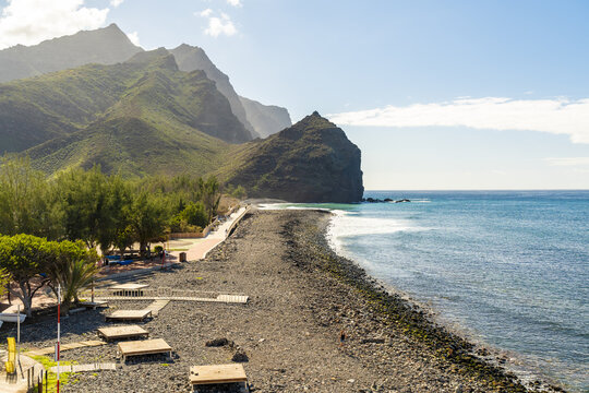 View of La Aldea de San Nicolas with a rocky beach, wooden platforms, and dramatic mountains in Las Palmas de Gran Canaria, Canary Islands, Spain.