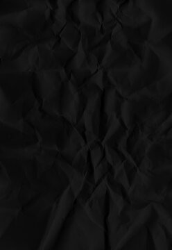 Black crumpled paper texture with dramatic shadows provides a dark aesthetic background for moody graphic design projects requiring depth and organic tactile folded visual elements.