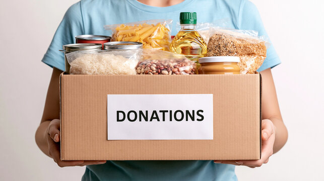 Food Donation Box: A person holds a cardboard box filled with essential food items, labeled DONATIONS, ready to be distributed to those in need. A symbol of generosity and community support.