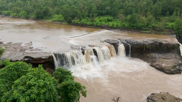 Gira waterfall located in Waghai village near Saputara hill station Gujarat,India. A scenic monsoon landscape featuring a powerful muddy-water waterfall cascading over a rocky plateau.