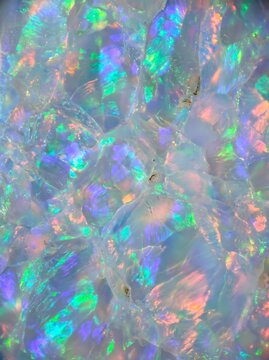 Iridescent opal mineral macro in a potrait orientation showcases a shimmering crystalline texture for luxury branding, digital art backgrounds, and jewelry design templates.