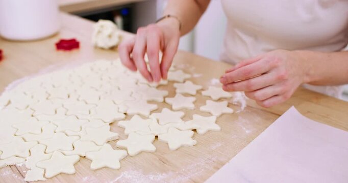 Cooking sweets. Festive pastry recipe. Baker female hands making star shape white cookies on wooden countertop from flour dough sheet.