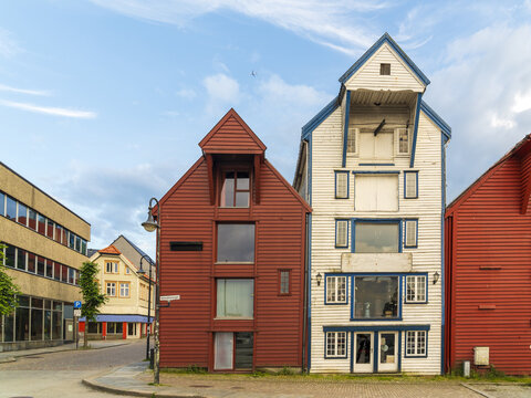 View of historic wooden buildings in the city center of Stavanger, featuring traditional red and white facades under a blue sky in Stavanger, Rogaland, Norway.