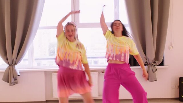 Entertainer rehearsal. Fun show. Laughing woman in bright costumes synchronous stepping in energy rhyme training party in modern studio.
