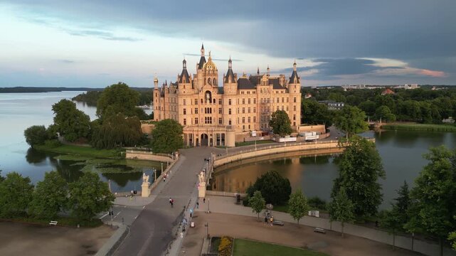 Schwerin Castle, Schwerin, Mecklenburg-Vorpommern, Germany. Schwerin Castle glows during golden hour. Schwerin Castle rises above Palace Island. Historic Schwerin Castle reflects in surrounding water.