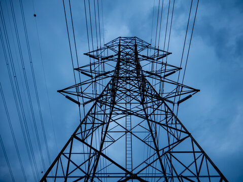 High Voltage Electricity Transmission Tower Pylon Viewed from Below Against Dusk Sky