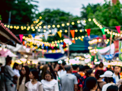 Blurred Crowd at Night Market with Bokeh String Lights and Colorful Flags