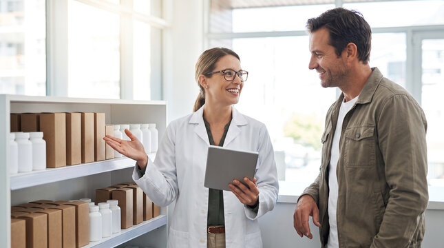 Pharmacist explains over-the-counter healthcare options to customer in modern pharmacy, supporting medication guidance, wellness, patient service and informed health decisions with copy space.
