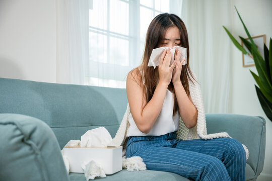 Asian young woman she sick blowing nose sneezing in tissue at home