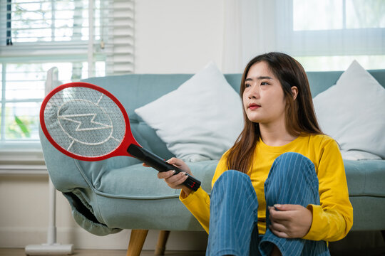 Woman killing mosquitoes hand holding fly swatter like weapon