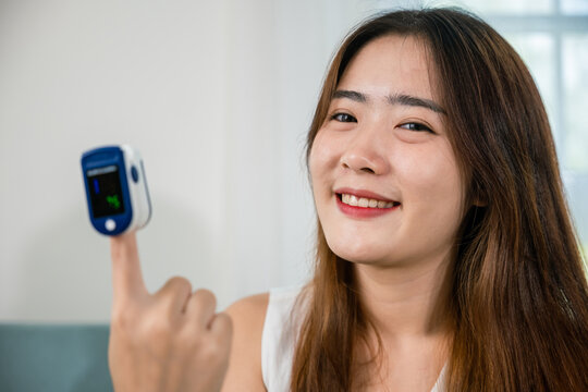 Young woman using pulse oximeter to monitor blood oxygen levels and pulse rate on finger