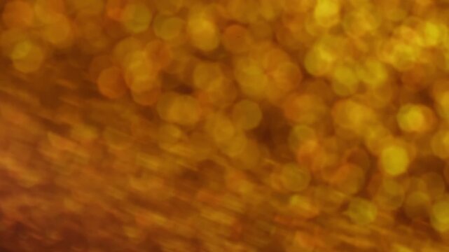 Shimmering dots. Hypnotic blur glow. Defocused color light transition rotate optic lens. Mystic bokeh orange yellow rays circles abstract background.