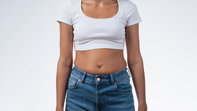 Female Torso With Belly In Jeans On White Studio Background Copy Space