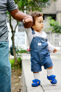 Daddy and his toddler son walking in the street.