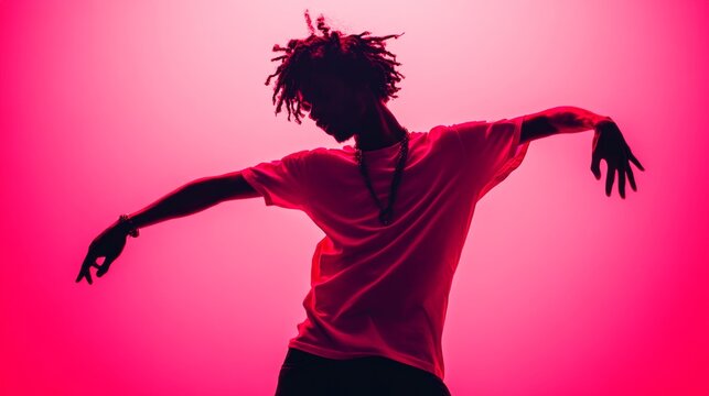 Energetic young man dancing in silhouette against a vibrant neon pink studio background lighting