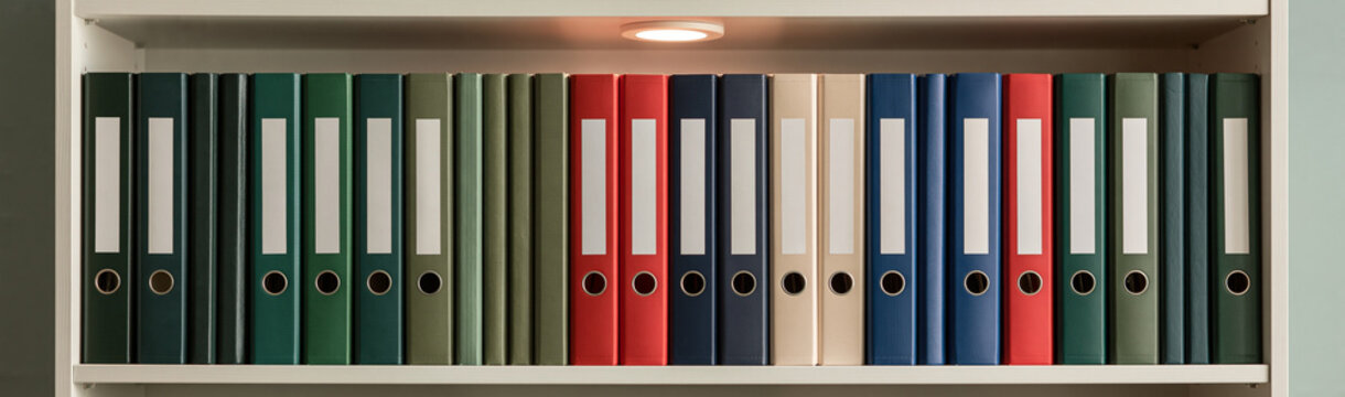 Organized Archive of Binders: A neatly arranged shelf filled with colorful binders, showcasing a systematic approach to document organization and information storage.