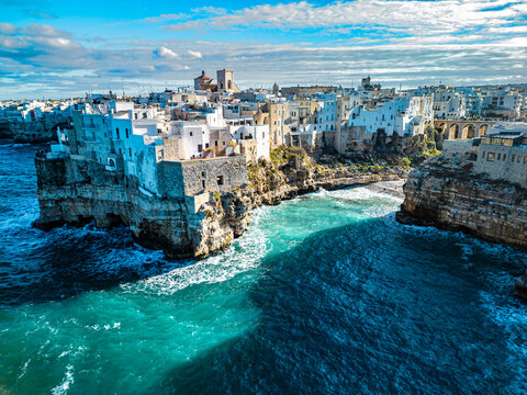 Aerial view of the historic town of Polignano a Mare perched on limestone cliffs above the turquoise Adriatic Sea in Polignano a Mare, Apulia, Italy.