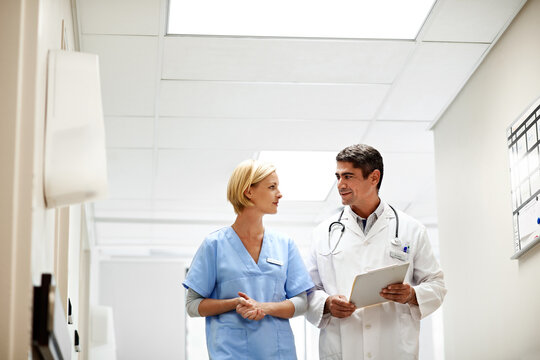 Doctor, nurse and walking in hospital at clipboard, medical report and patient chart for diagnosis. Healthcare, people and teamwork in workplace with checklist, pathology results and surgery outcome