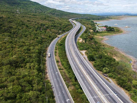 Drone aerial view of Motorway M6 Bang Pa-in&ndash;Nakhon Ratchasima expressway running beside Lam Takhong Reservoir in Nakhon Ratchasima, Thailand under cloudy skies