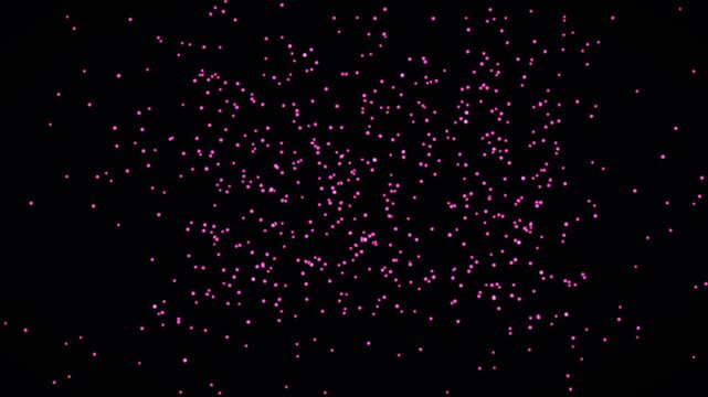 Small pink particles move and float in a dark space. The scene shows a dynamic pattern that shifts and changes, creating a sense of movement and depth
