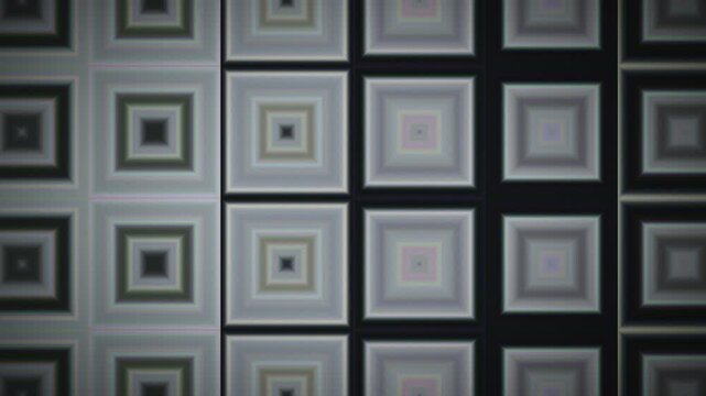 A series of squares arranged in a grid pattern on a wall creates a geometric effect. The design features varying shades of black, white, and gray. The shapes give a modern look