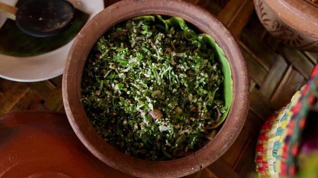 A clay pot filled with fresh green coconut mallung salad of chopped leaves and grated coconut, a healthy side dish of traditional Sri Lankan village cuisine.