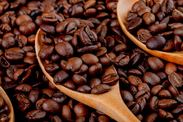 Naklejka premium Roasted Coffee Beans in Wooden Spoons Close Up Background