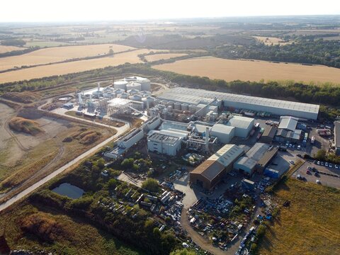 Aerial view of the RenEco waste management and recycling facility featuring industrial buildings, storage tanks, and equipment surrounded by rural fields in Wymington, England, United Kingdom.