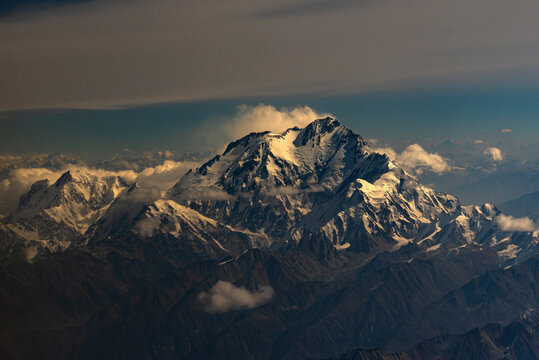 Aerial view of Nanga Parbat mountain peak rising above the surrounding snow-capped Himalayan range with dramatic clouds and rugged terrain Himalayas, Gilgit Baltistan, Pakistan.