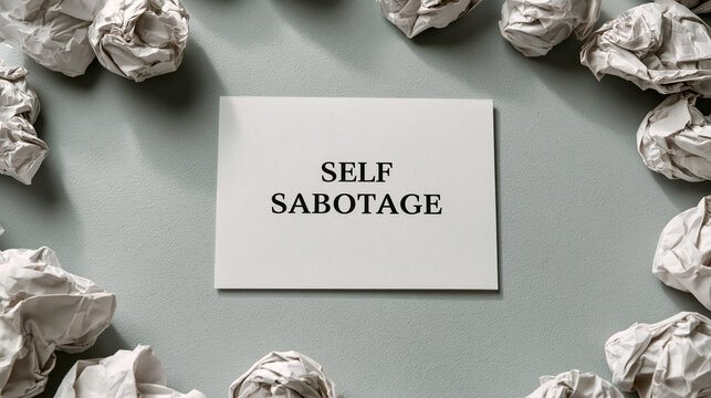 Self Sabotage Message Surrounded by Crumpled Paper: A stark white card with the words SELF SABOTAGE prominently displayed, encircled by numerous crumpled balls of paper.