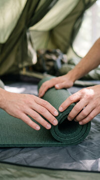 Rolling up green sleeping pad mat inside camping shelter tent