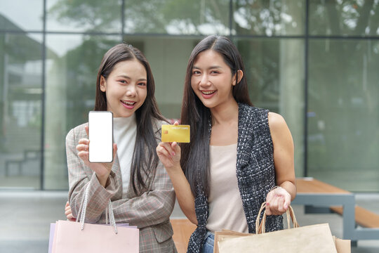 Asian women holding credit card and blank smartphone screen for Black Friday shopping