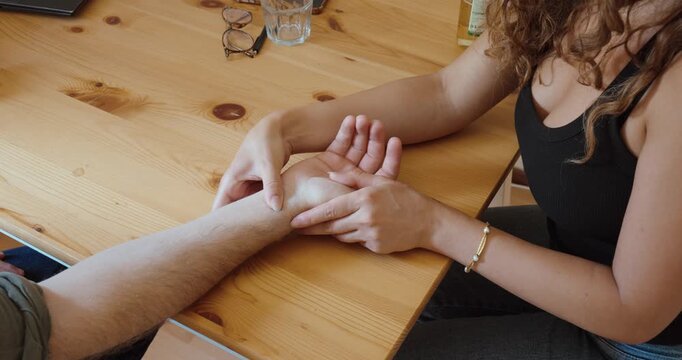 A woman manually checks a man's pulse by hand to assess his condition during a medical emergency.