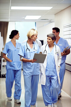 Clipboard, hospital and doctors walking in corridor for discussion, patient report and consulting. Healthcare, nurses and people in hallway for talking, surgery advice and meeting for medical service
