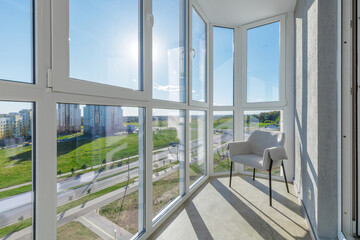 Fototapeta premium Modern Glazed Balcony Interior with Armchair and Panoramic View
