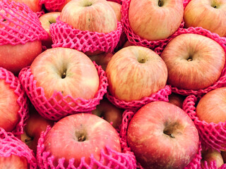 Bright red apples nestled in pink mesh bags. Fruits look fresh, smooth, and slightly shiny. Colorful packaging suggests a market or retail setting. Ideal for food, agriculture. Appeal evokes freshness © Shutterofadam