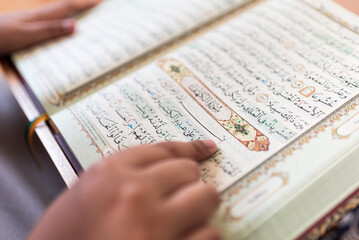 Obraz premium Intimate perspective highlights foundational scripture literacy while a dedicated youthful scholar actively traces sacred Arabic text emphasizing profound spiritual connectivity