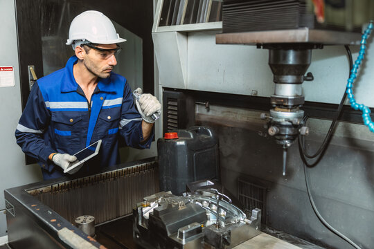 Worker Operates EDM Machine inspecting Metal injection mold production in Thermoplastic Factory.