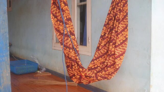 Traditional baby cradle made of Javanese batik cloth hung inside the house, a typical Indonesian rural habit of putting babies to sleep.