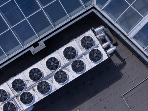 Aerial view of industrial HVAC cooling units installed on a flat rooftop with a glass skylight in Gdansk, Poland.