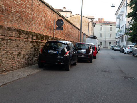 Lancia Ypsilon parked on a narrow Italian street alongside a historic brick wall in an urban setting