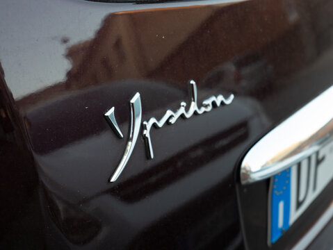 Lancia Ypsilon car model name badge on dark maroon trunk, showing automotive brand details