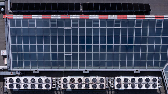 Aerial view of a modern building roof featuring a large glass skylight, rows of industrial HVAC cooling units, and solar panels in Gdansk, Poland.