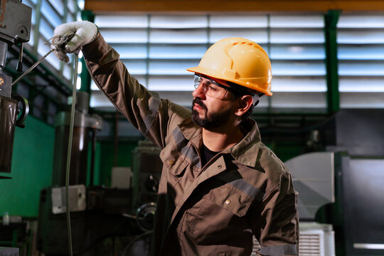Professional male technician cleaning heavy machinery with air blow gun in factory plant