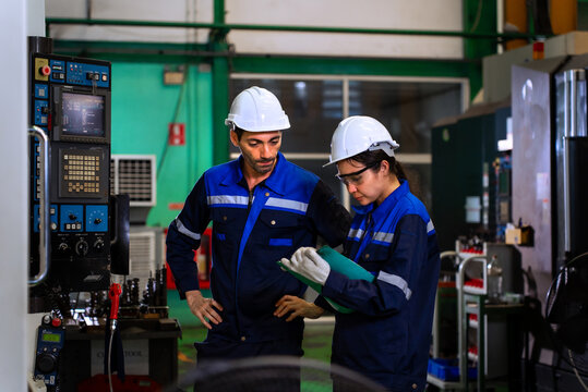 Industrial engineers inspecting cnc machine operation with clipboard in modern factory. ideal for manufacturing, automation, and industry 4.0 marketing campaigns.
