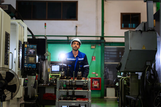 Industrial worker operating cnc machine equipment in modern manufacturing plant for industrial automation concept.