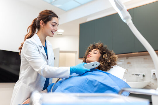 Female dermatologist or doctor in gloves performing a laser skin treatment or facial procedure on a woman in a clinic. Aesthetic medicine and skincare treatment concept.