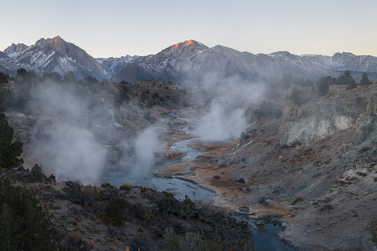 Steaming hot spring landscape in sierra nevada mountain valley evokes serene wonder under clear twilight sky with distant snow peak